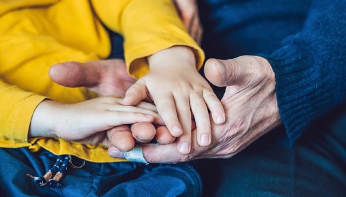 The hands of an elderly person and the hands of a child, the continuity of generations, the care of the elderly.